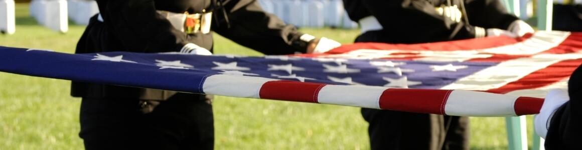 A folded American flag being held by active military members to honor their sacrafice.