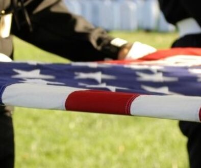 A folded American flag being held by active military members to honor their sacrafice.