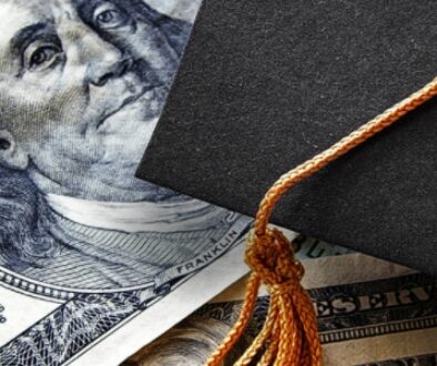 A black graduation cap with an orange tassel on a 100 dollar bill for scholarship recipients.