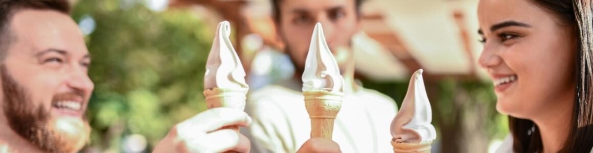 Three friends holding up ice cream cones representing an ice cream party.