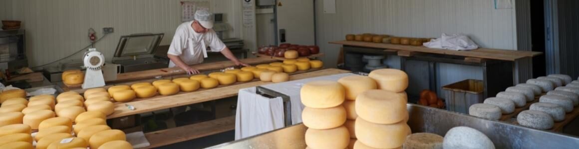A man working in a room with cheese wheels representing U.S. cheese production.